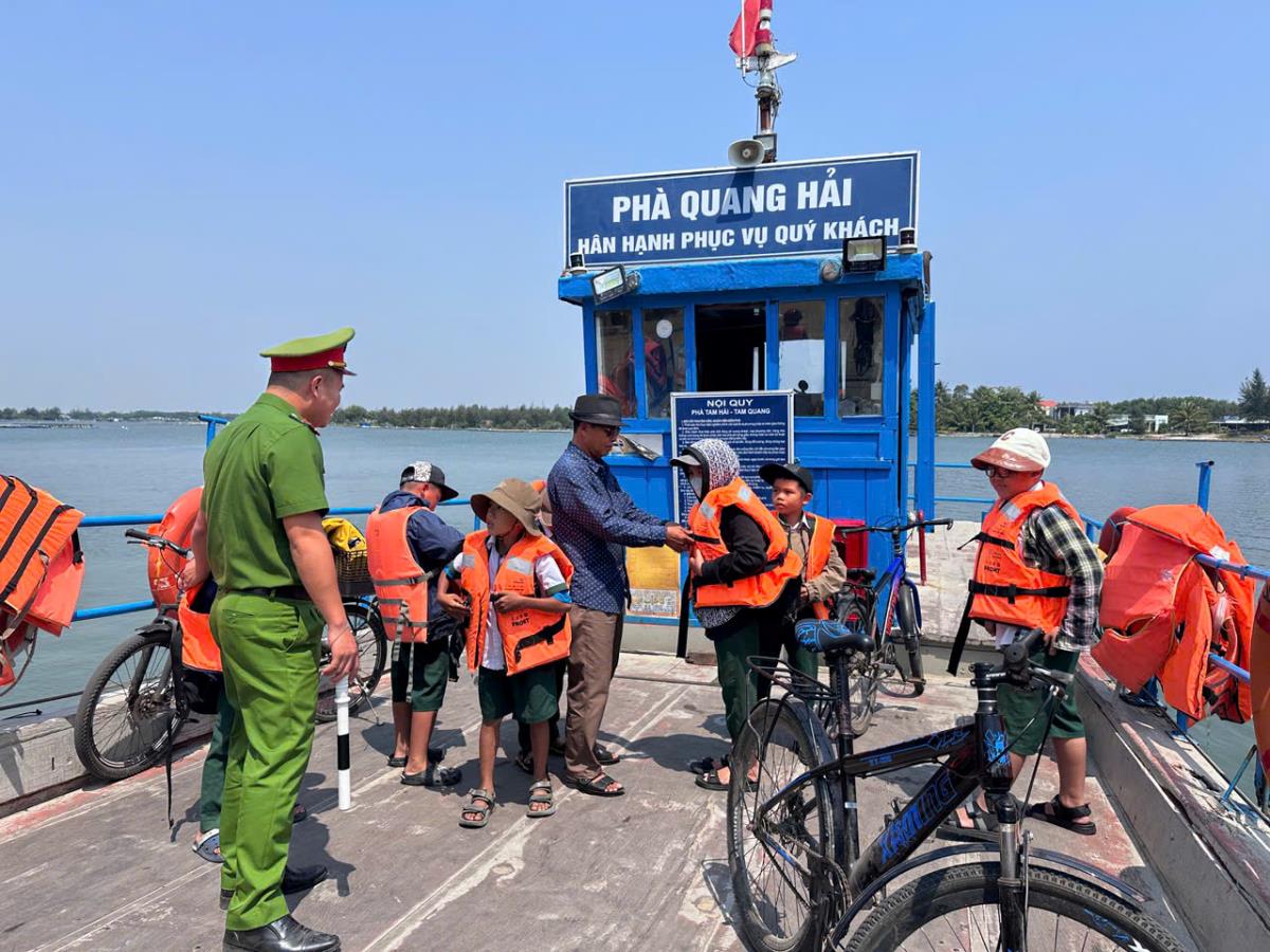 Công an xã Tam Hải nhắc nhở các học sinh mặc áo phao đúng cách khi đi phà.