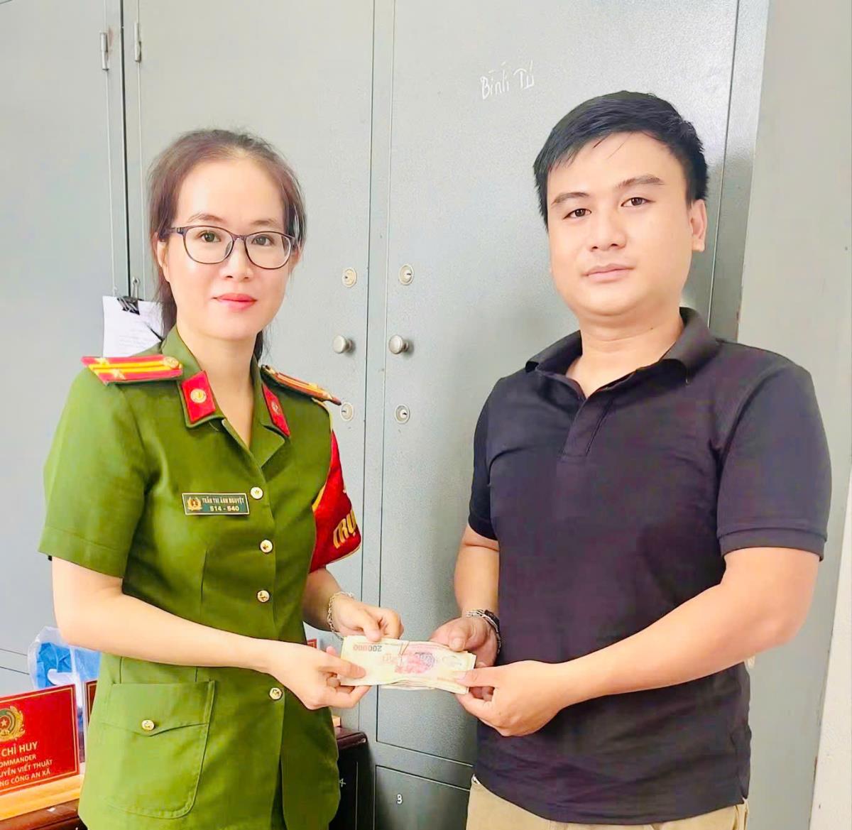 Anh Nhi bàn giao số tiền nhặt được cho Công an xã Thăng Điền.