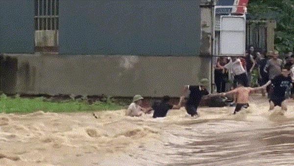 Thót tim cảnh đoàn người nối tay nhau kéo giữ nạn nhân và xe máy bị lũ cuốn
